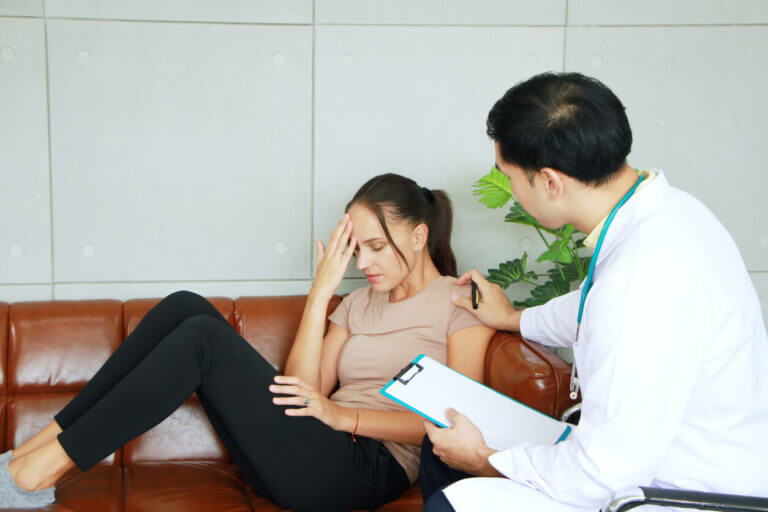 A psychiatrist is counseling and encouraging a Caucasian female who is experiencing an anxiety disorder.