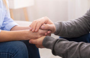 A psychiatrist is counseling his patient while holding hands during therapy for anxiety.