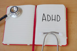 The acronym ADHD written in a medical notebook with a stethoscope, symbolizing attention deficit hyperactivity disorder in clinical context.
