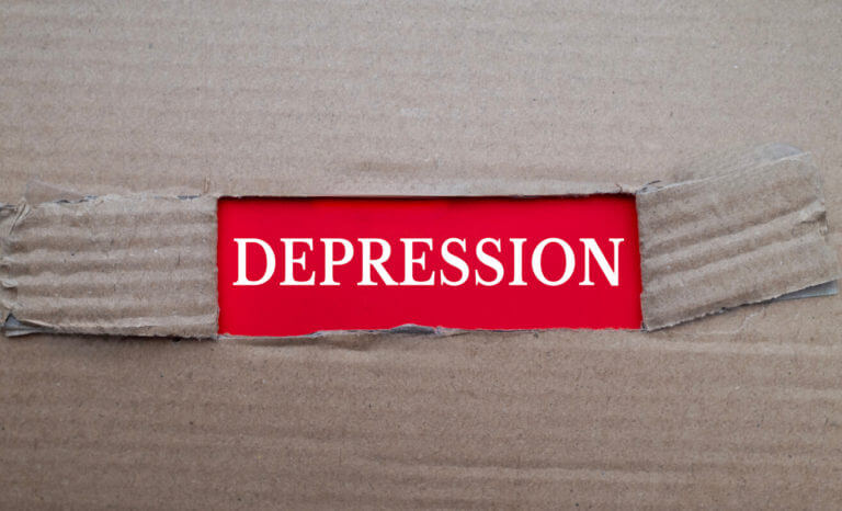 Depression text on red paper over torn card box background.