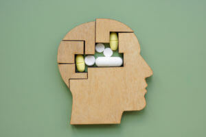 Puzzle shaped like a head and pills symbolizing mental health and medication.