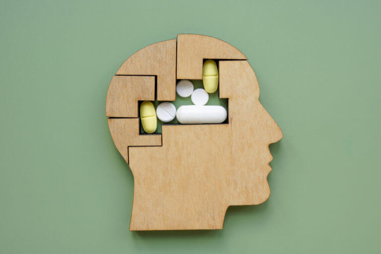 Puzzle shaped like a head and pills symbolizing mental health and medication.